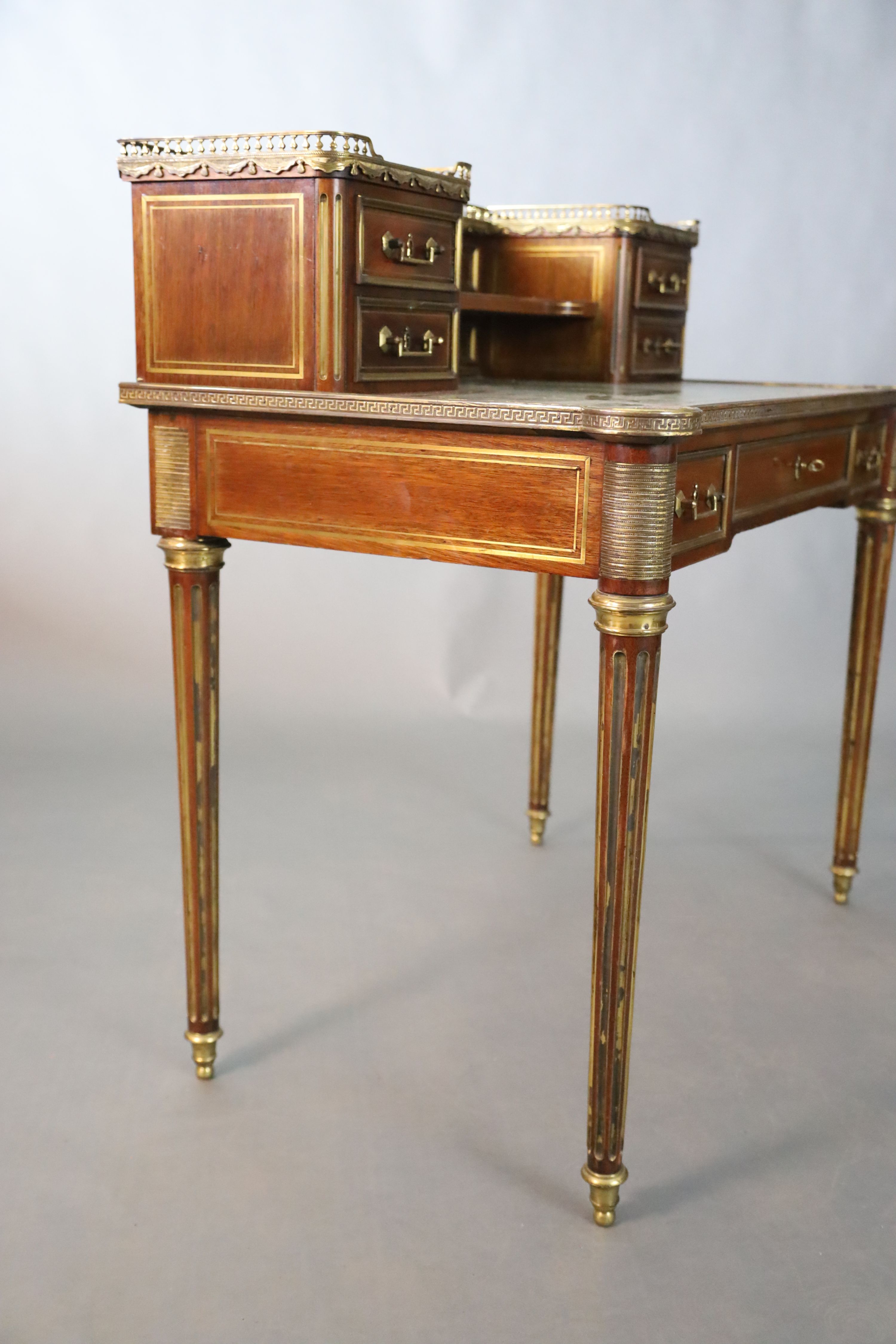 A French Louis XVI style brass mounted marble inset mahogany writing table, W.101.5cm D.7.5cm H.93.5cm